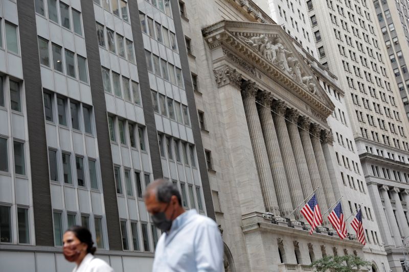 FILE PHOTO: People wearing face masks walk by the NYSE during the COVID-19 outbreak in New York City, New York