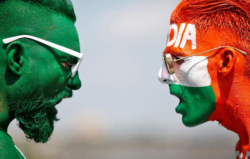 Cricket fans, with their faces painted in the Indian and Pakistani national flag colours, pose for a picture in Ahmedabad