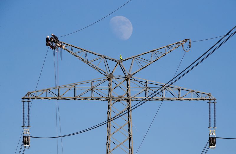 FILE PHOTO: The moon rises as electricians work atop a power pole near the lignite power plant of Neurath of German energy supplier and utility RWE, near Rommerskirchen