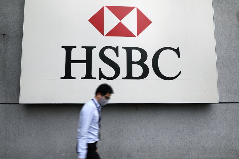 FILE PHOTO: A man wearing a protective mask walks past a logo of HSBC at its headquarters, amid the coronavirus disease (COVID-19) outbreak in Kuala Lumpur
