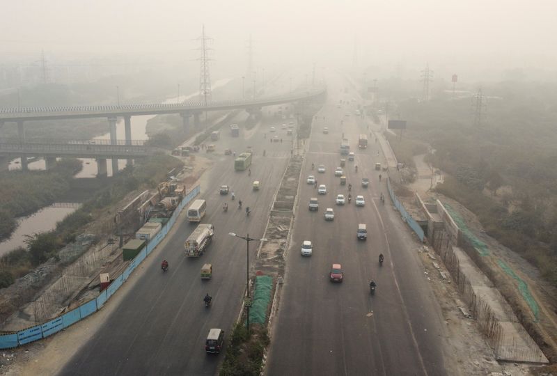 Traffic moves on a highway shrouded in smog in New Delhi