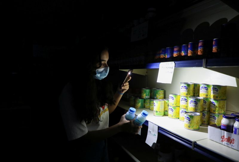 A customer uses her phone's torch light in a grocery store during a power cut near Bhamdoun