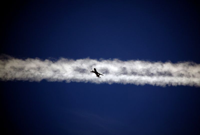 FILE PHOTO: An aeroplane flies underneath the jet stream of another aircraft above the Italian city of Padova