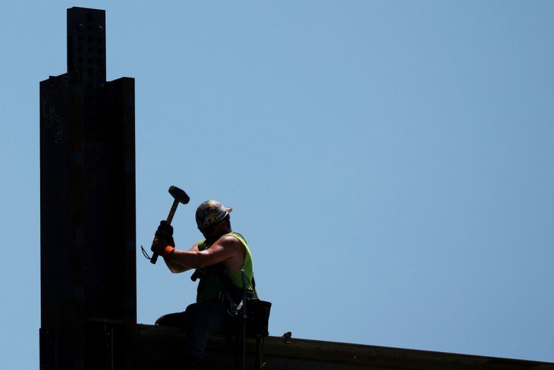 FILE PHOTO: Construction workers install steel beams on high-rise building during a summer heat wave in Boston