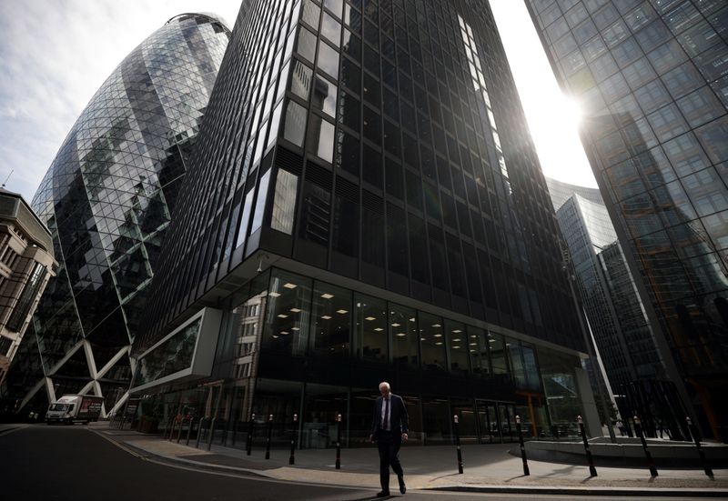 FILE PHOTO: A person walks through the City of London financial district in London