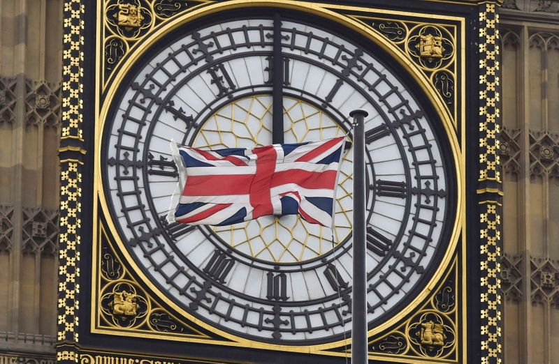 FILE PHOTO: A British Union flag flutters in front of one of the clock faces of the 'Big Ben' clocktower of The Houses of Parliament in central London