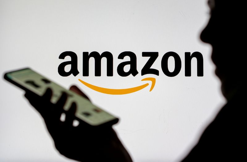 FILE PHOTO: FILE PHOTO: Woman with smartphone is seen in front of displayed Amazon logo in this illustration taken