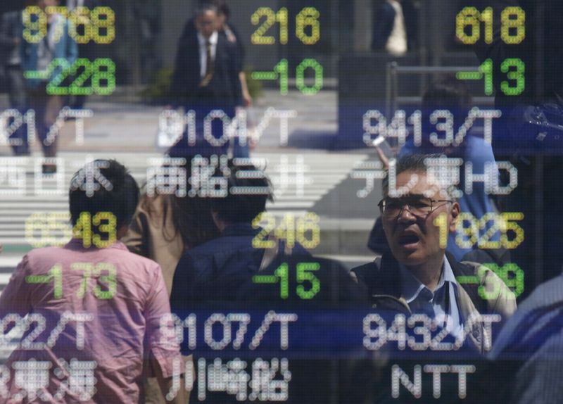 People are reflected in a stock quotation board outside a brokerage in Tokyo