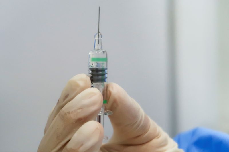 FILE PHOTO: A nurse holds a syringe containing a coronavirus disease (COVID-19) vaccine by Sinopharm at a vaccination center in Beijing