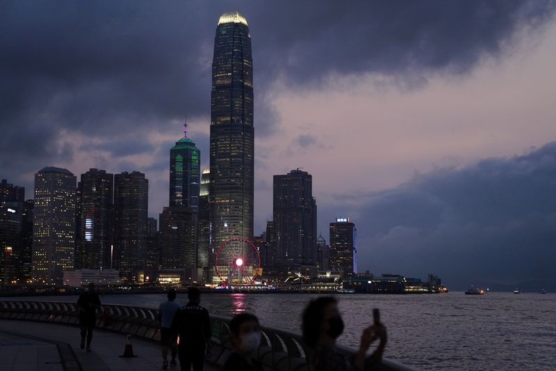 FILE PHOTO: Woman takes pictures in front of high-rise buildings in the Central financial district after sunset in Hong Kong