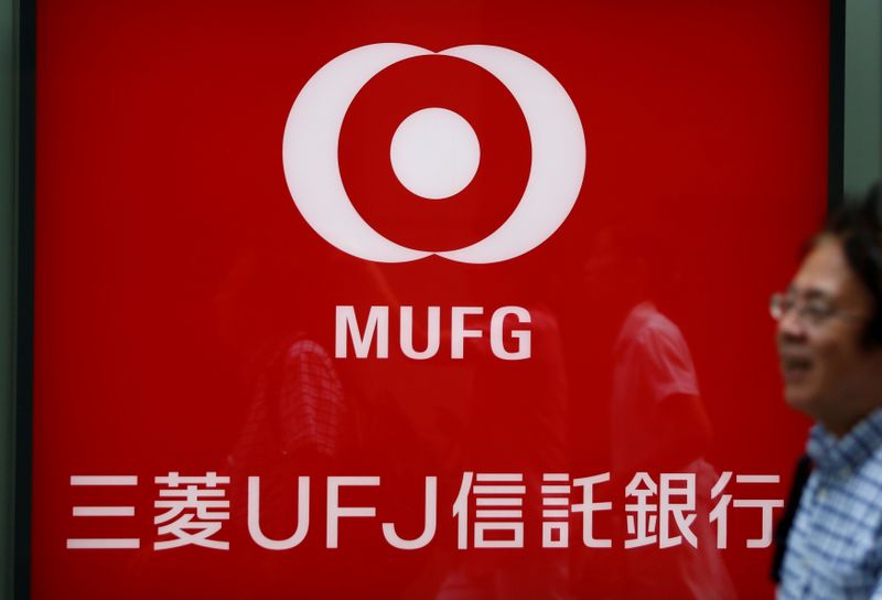 A man walks past in front of a sign board of Mitsubishi UFJ Trust and Banking Corporation in Tokyo