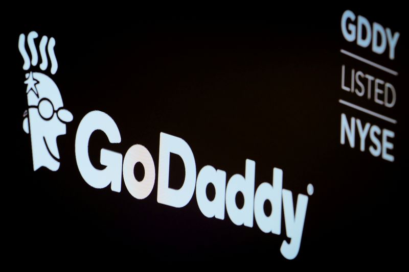 FILE PHOTO: The company logo and ticker for GoDaddy Inc. is displayed on a screen on the floor of the NYSE in New York