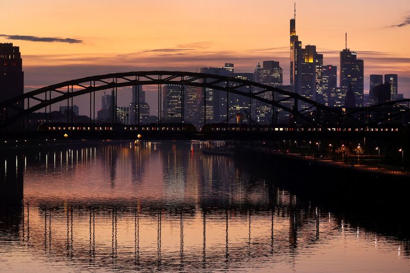 FILE PHOTO: A commuter train passes by the skyline of the financial district in Frankfurt