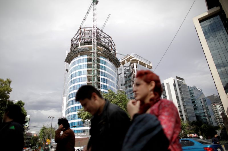 FILE PHOTO: People walk past a building undergoing construction in Mexico City