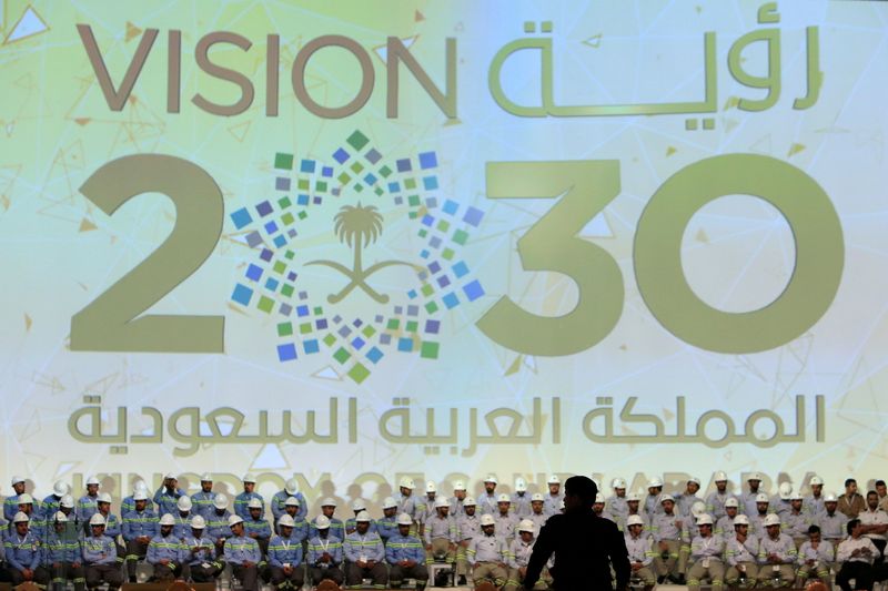 FILE PHOTO: Large banner shows Saudi Vision for 2030 as a soldier stands guard before the arrival of Saudi King Salman at the inauguration of several energy projects in Ras Al Khair