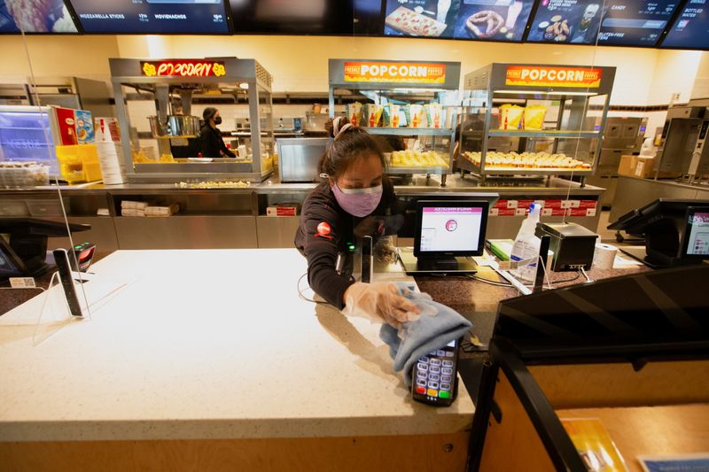 A member of the staff sanitizes a credit card machine at a AMC theatre on reopening day during the outbreak of the coronavirus disease (COVID-19), in Burbank