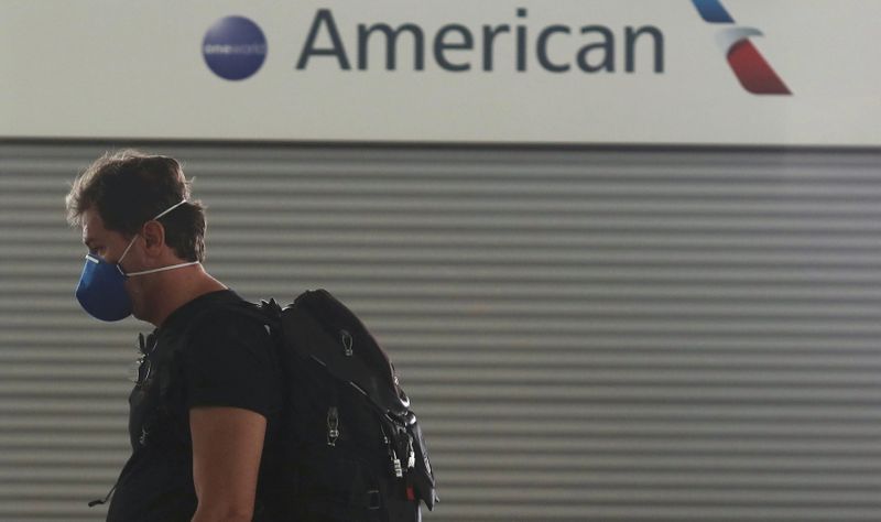 FILE PHOTO: Passenger wears a protective face mask as he walks past the American Airlines ticketing desk at Josep Tarradellas Barcelona-El Prat Airport, after further cases of coronavirus were confirmed in Barcelona