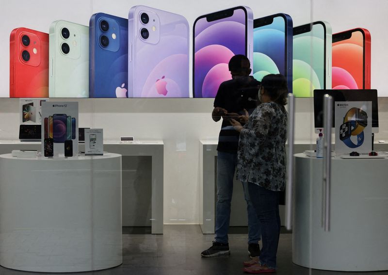 FILE PHOTO: A salesperson speaks to a customer at an Apple reseller store in Mumbai