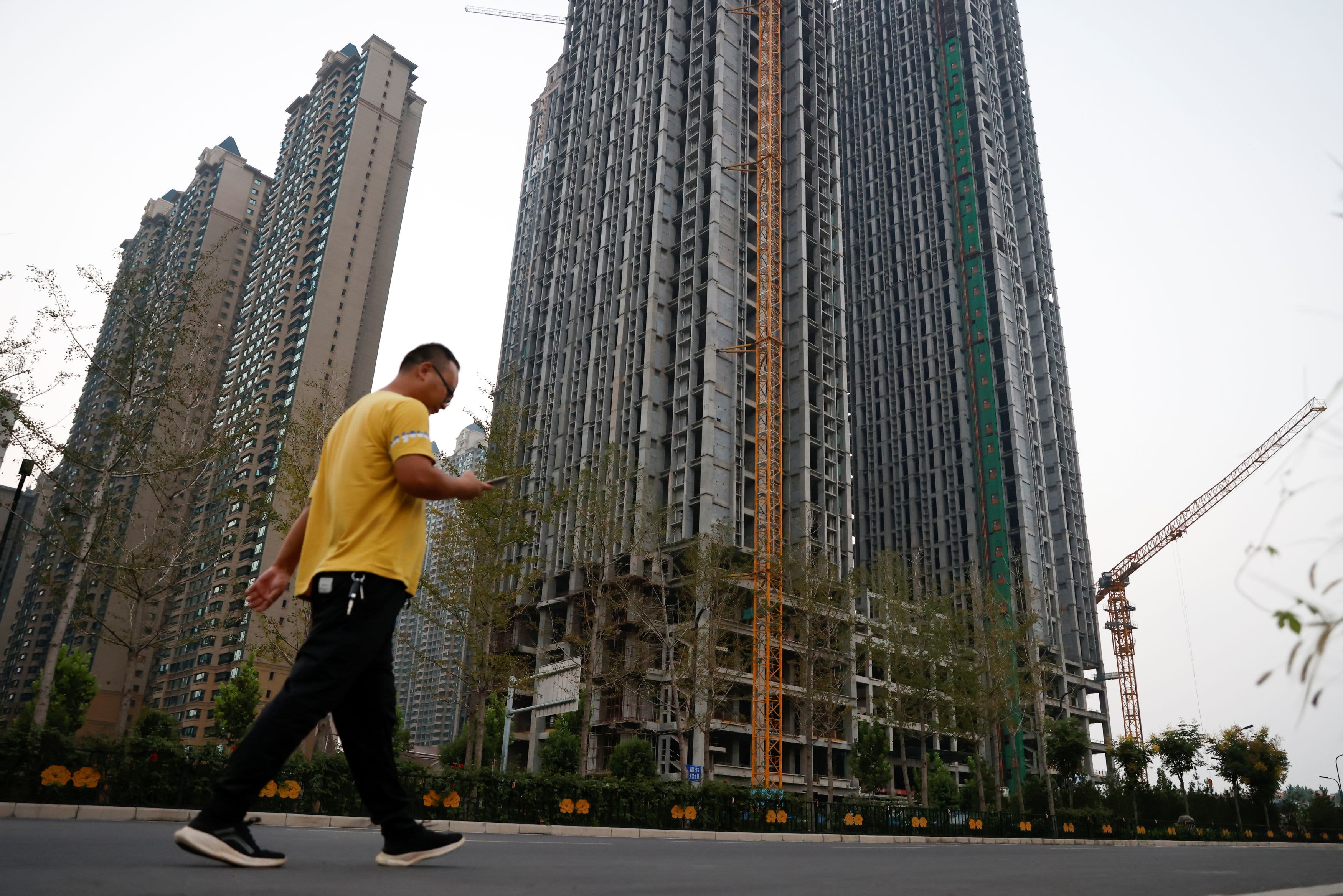 A man walks in front of unfinished residential buildings at the Evergrande Oasis, a housing complex developed by Evergrande Group, in Luoyang, China September 15, 2021. Picture taken September 15, 2021.