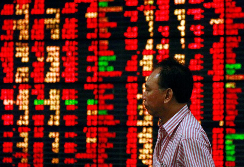 FILE PHOTO: An investor walks past an electronic board displaying live market data at a stock broker's office in central Bangkok