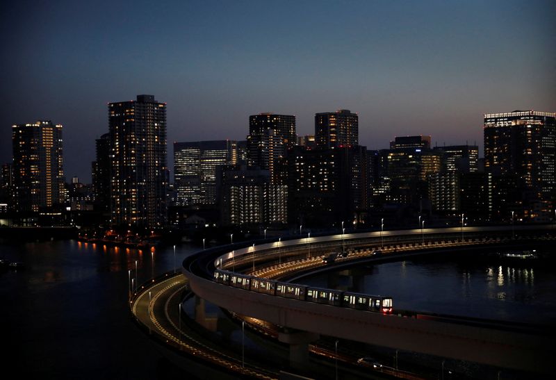A Yurikamome line train runs with city skyline in background, in Tokyo