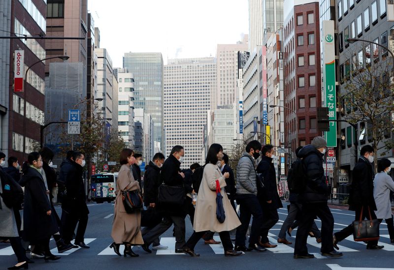 FILE PHOTO: Pedestrians wearing protective masks, following the coronavirus disease (COVID-19) outbreak, make their way during commuting hour at a business district in Tokyo
