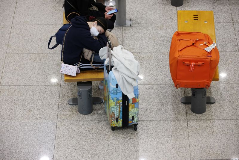 A woman wearing a mask to prevent contracting COVID-19 naps at the Incheon International Airport in Incheon