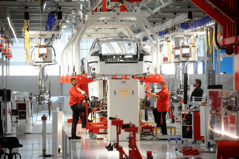 FILE PHOTO: Tesla workers examine a Model S used for training and tool calibration at the company's factory in Fremont