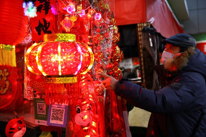 A customer looks at decorations for Chinese Lunar New Year displayed at a stall inside a morning market in Beijing