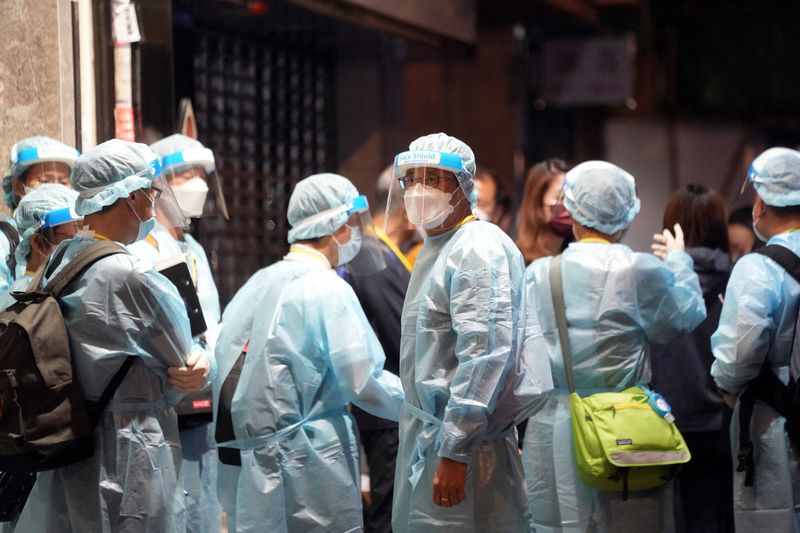 Workers in protective suits arrive to a building under lockdown for compulsory testing in Hong Kong