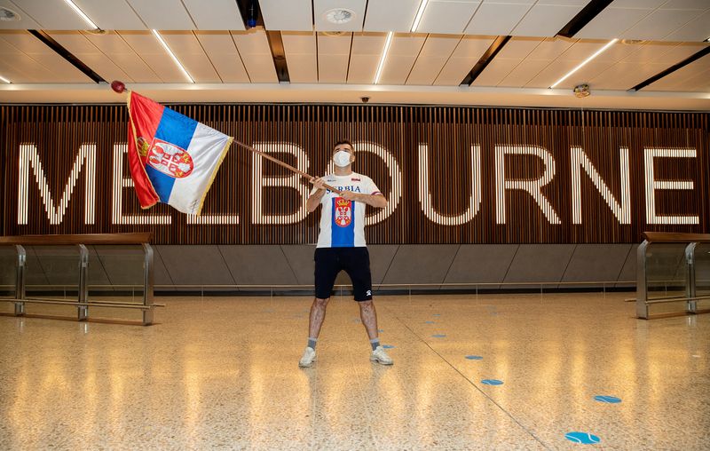 A fan of Serbian tennis player Novak Djokovic is seen waving a Serbian flag while awaiting the arrival of Djokovic at Melbourne International Airport