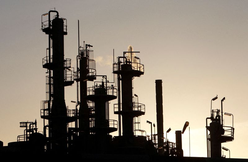 FILE PHOTO: Towers and smokestacks are silhouetted at an oil refinery in Melbourne