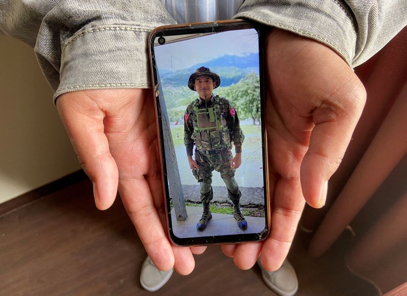 Kaung Thu Win shows a photograph of himself wearing an army uniform on his mobile phone, during an interview with Reuters at an undisclosed location