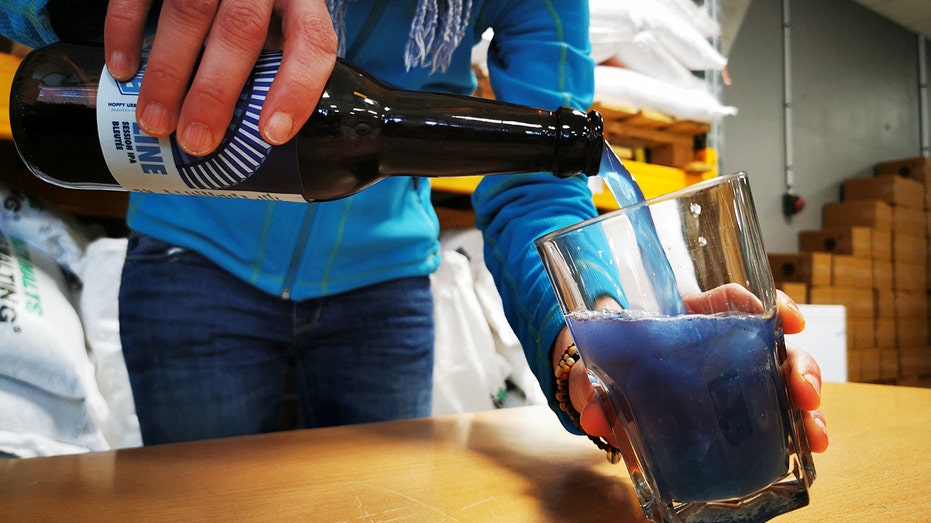 Person pours blue beer