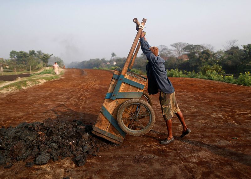 FILE PHOTO: A labourer unloads fertilizer for drying at a factory in Kolkata
