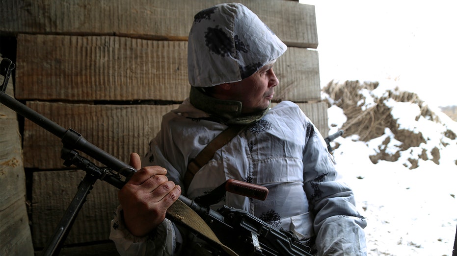 A serviceman holds his machine gun in a shelter on the territory controlled by pro-Russian militants at the front line with Ukrainian government forces in the Slavyanoserbsk, Luhansk region, eastern Ukraine, Tuesday, Jan. 25, 2022. 