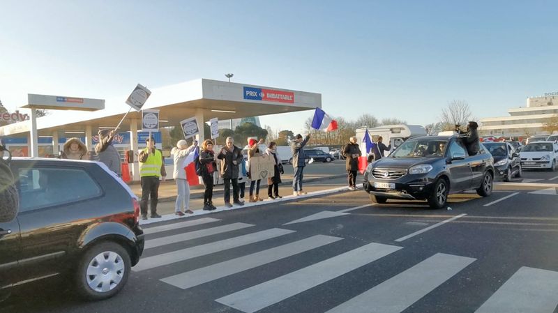 People gather as a vehicle convoy with French and Canadian flags passes, in Nantes