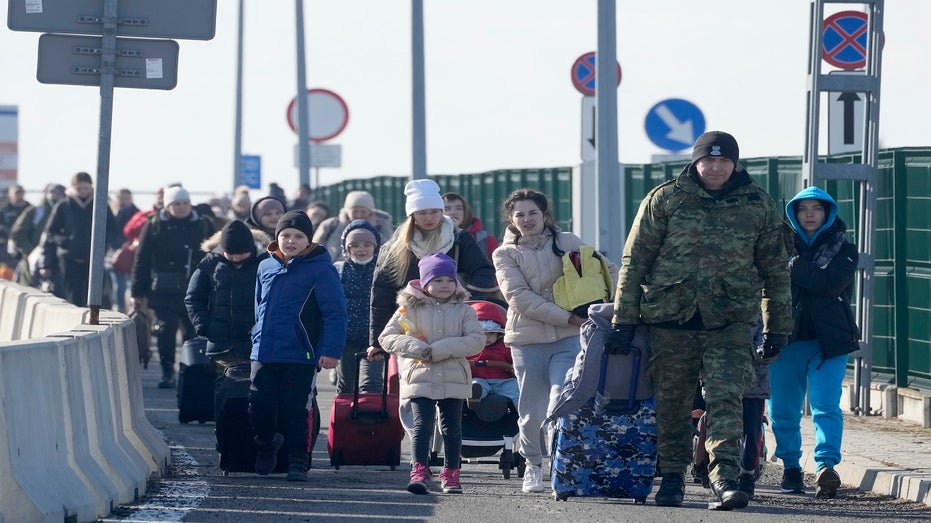 A Polish border guard assists refugees from Ukraine 