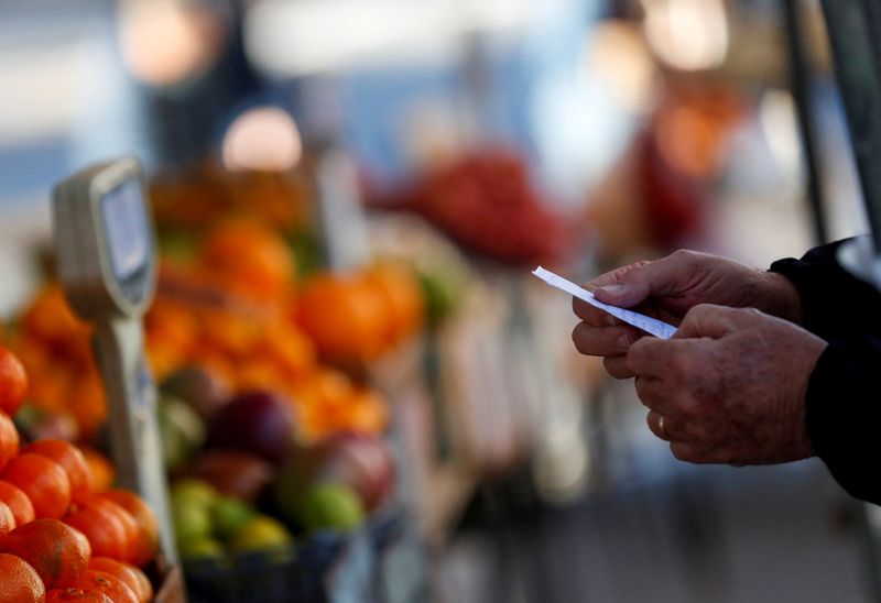 FILE PHOTO: A customer holds a shop list at a greengrocery store in a street market, in Buenos Aires