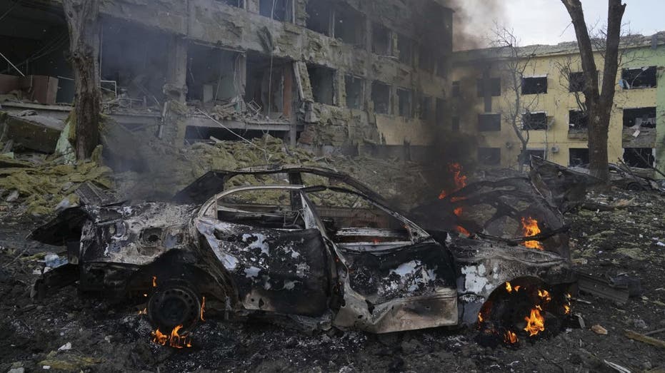 Car burns in front of bombed maternity hospital in Ukraine