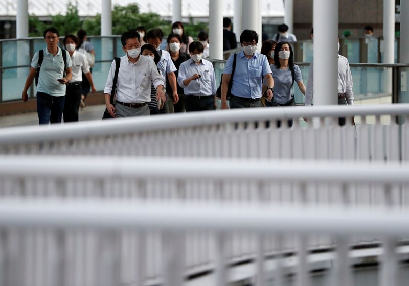Office workers wearing protective face masks head home during the spread of the coronavirus disease (COVID-19), in Tokyo