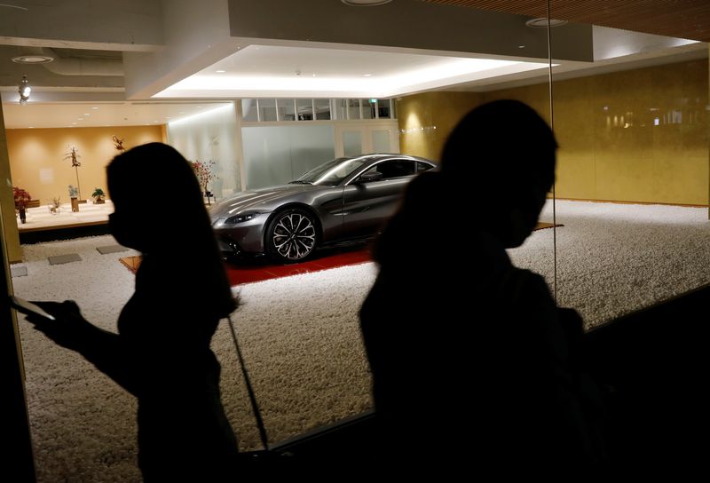 People wearing protective masks, amid the coronavirus disease (COVID-19) outbreak, walks past a shop selling luxury cars at Ginza shopping district in Tokyo