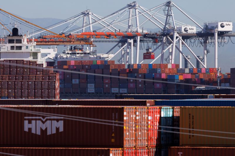 Stacked containers are shown as ships unload their cargo at the Port of Los Angeles