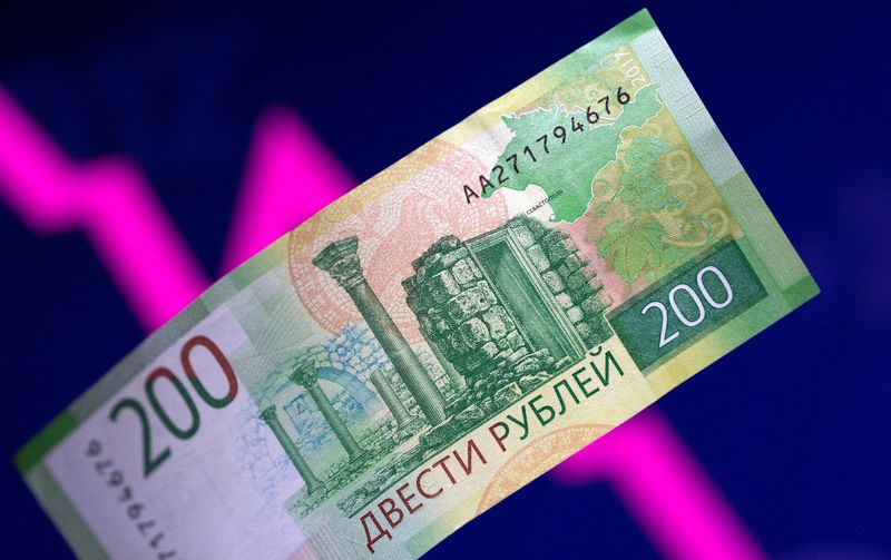 FILE PHOTO: Illustration shows a Russian rouble banknote and a descending stock graph