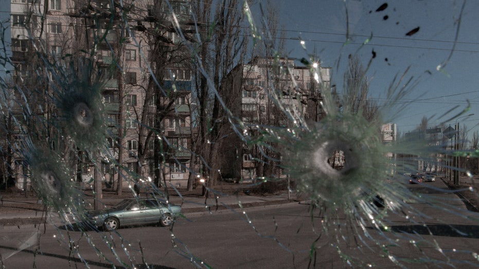 Cars are seen through the damaged window of a vehicle hit by bullets in Kyiv
