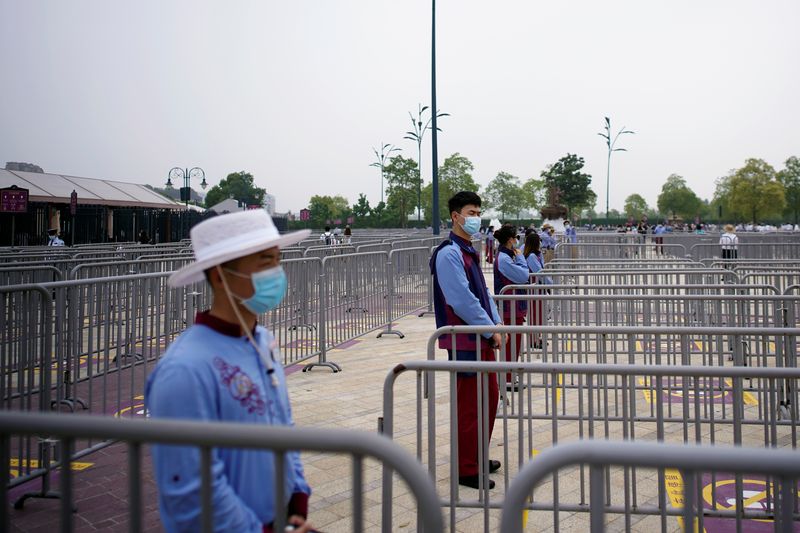 Staff members wearing face masks stand outside the Shanghai Disneyland theme park
