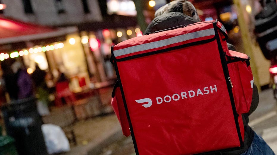 A door-dash delivery driver waits near a restaurant on Dec. 30, 2020, in New York City. 