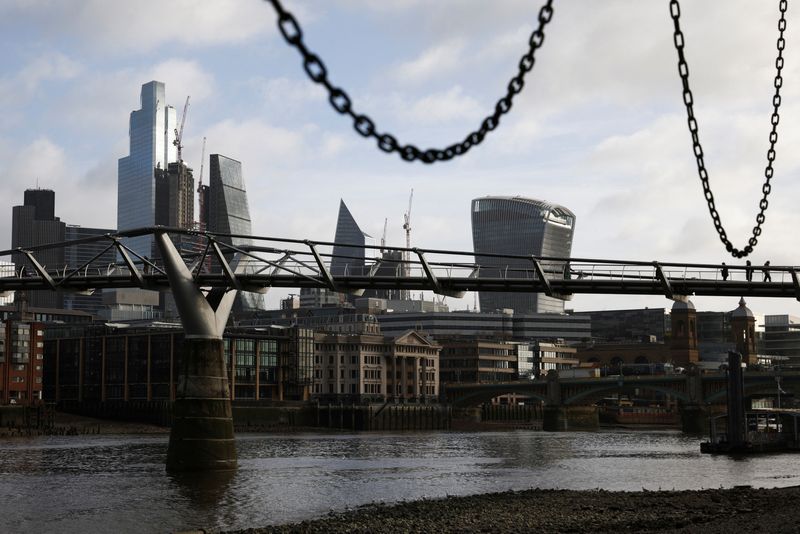 The City of London financial district is seen as people walk over Millennium Bridge in London