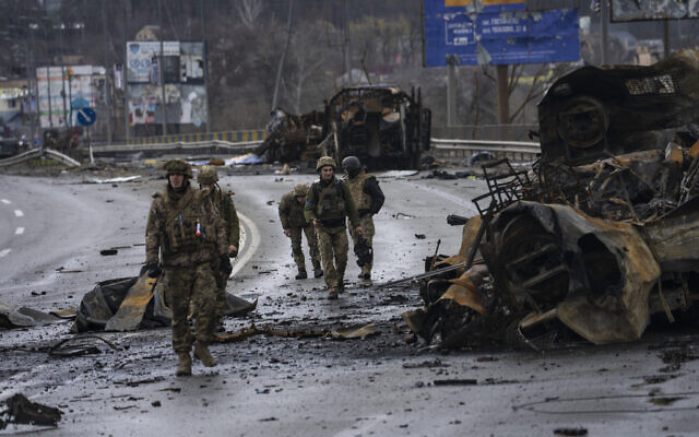 Ukrainian soldiers walk next to destroyed Russians armored vehicles in Bucha, Ukraine, Saturday, April 2, 2022. (AP Photo/Rodrigo Abd)