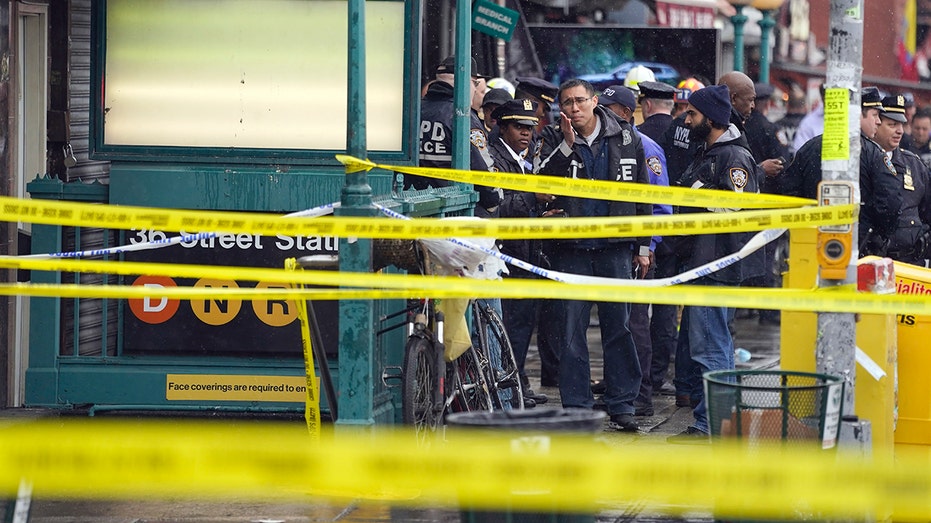New York Police stand outside a subway stop in Brooklyn where ten people were shot and six others injured.